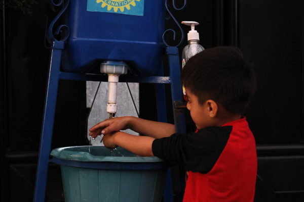 3.Jeune garçon utilisant un Tippy-Taps, une station de lavage des mains fabriquée avec une seringue pour limiter la consommation d'eau.